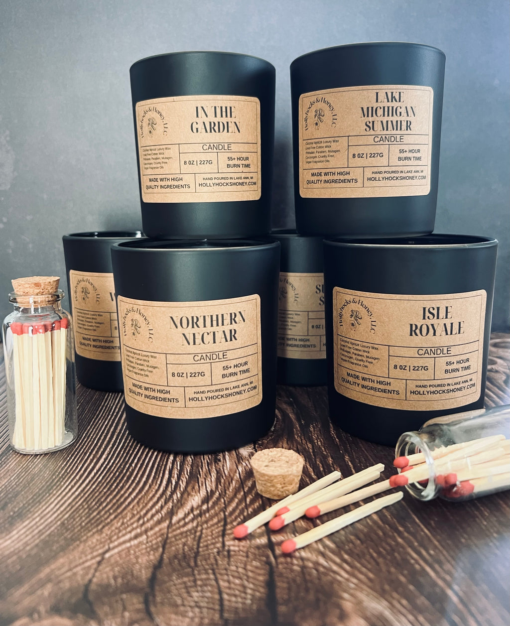 Collection of candles with labels on a wooden surface with matches.