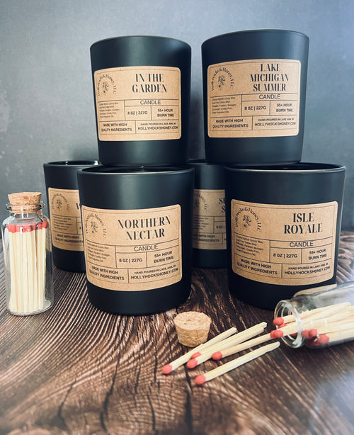 Collection of candles with labels on a wooden surface with matches.